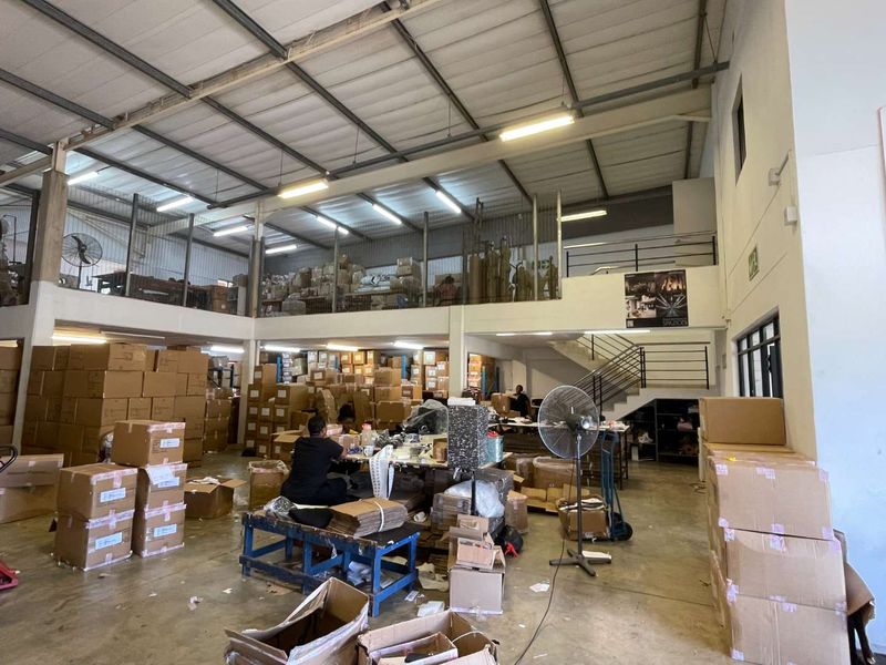 Spacious industrial warehouse unit featuring a mezzanine level, high ceilings with exposed steel trusses, and concrete flooring, suitable for storage or light manufacturing operations.