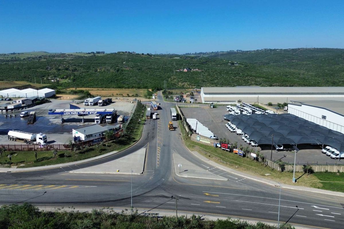 Aerial view of an industrial precinct featuring a truck stop, warehouse facilities, and extensive paved parking areas with shade structures.