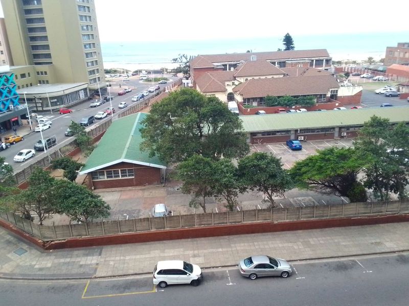An elevated aerial view of the surrounding urban neighborhood, featuring a parking lot, nearby buildings, and street access.