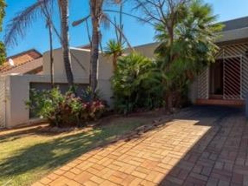 Front exterior view of the property featuring a brick paved driveway, established garden, and secure gated entrance.