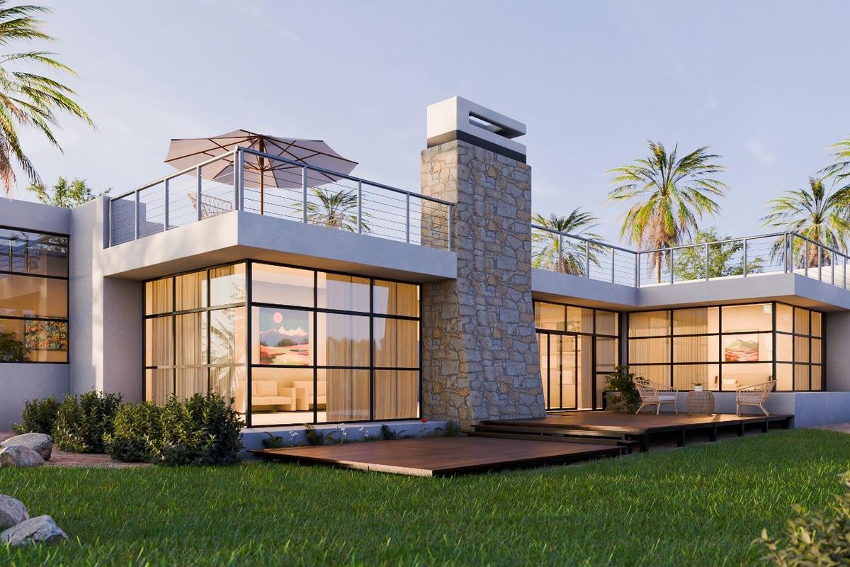 A modern architectural rear elevation featuring large steel-framed windows, a prominent stone chimney, and an expansive timber deck overlooking the garden.