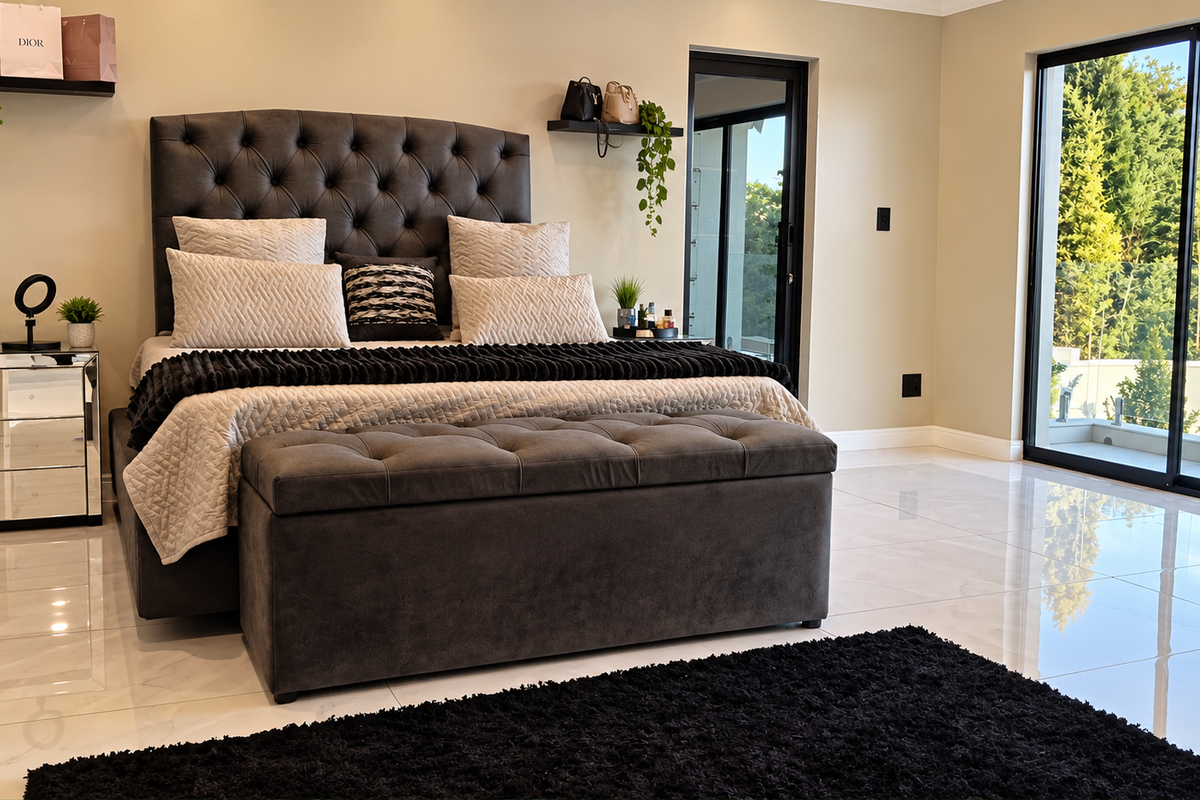 Spacious bedroom featuring polished tile flooring, modern sliding glass doors leading to a balcony, and a glass balustrade with scenic outdoor views.