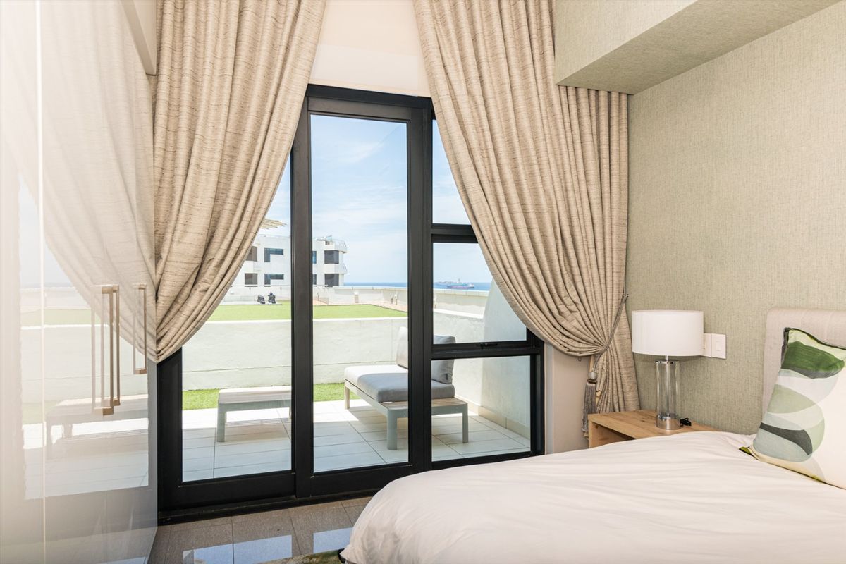 A well-maintained bedroom featuring large sliding glass doors that open onto a private balcony with ocean views.