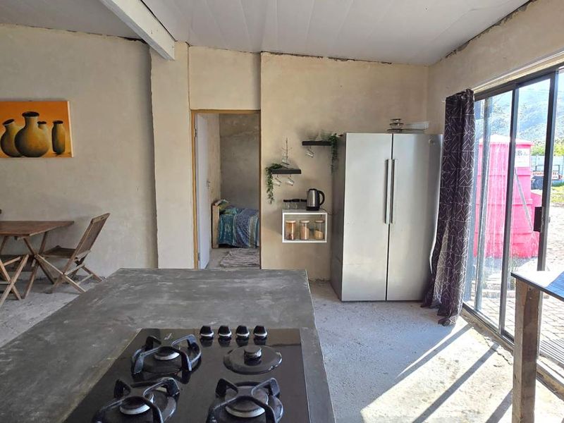 Open-plan living and kitchen area featuring a concrete island with a gas hob, subway tile backsplash, and direct access to the exterior via sliding doors.