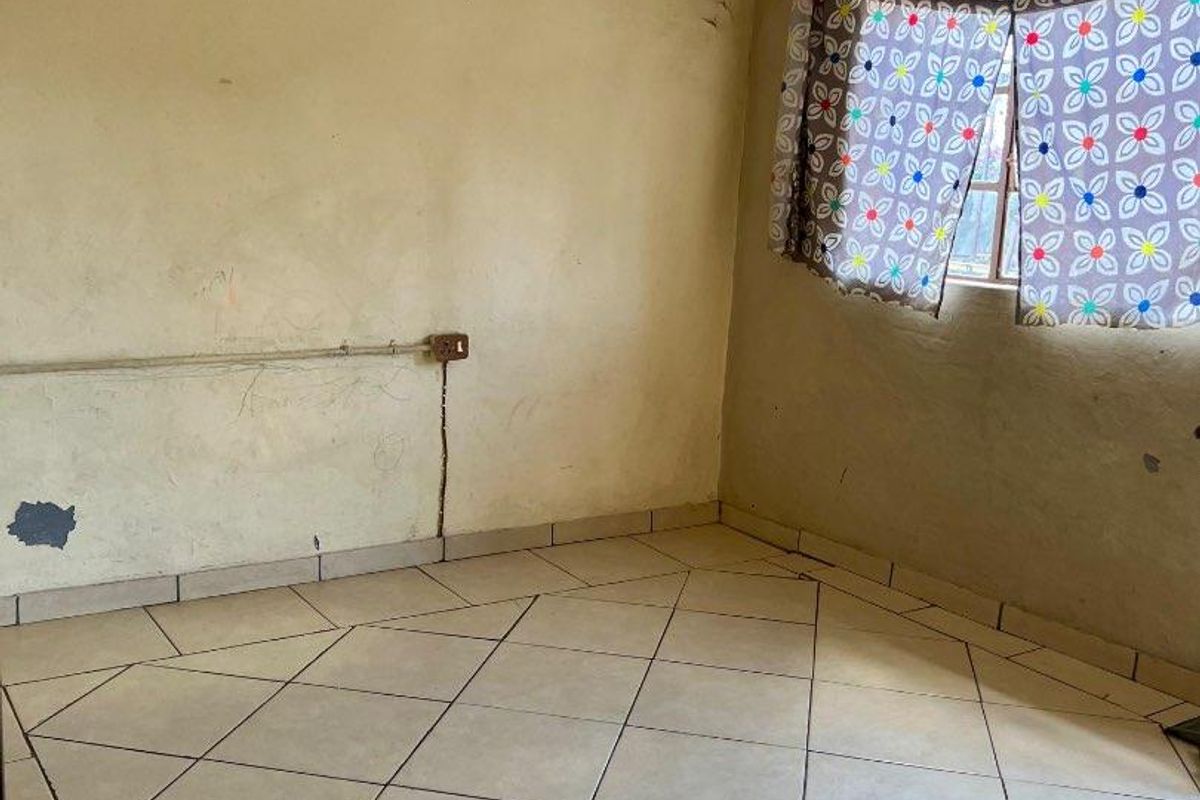 An empty bedroom featuring tiled flooring and visible wall wear, offering a blank canvas for renovation and modernization.