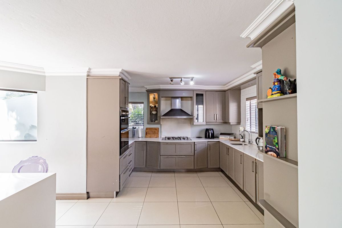 Modern kitchen featuring neutral cabinetry, stone countertops, built-in oven, gas hob, extractor fan, and tiled flooring.