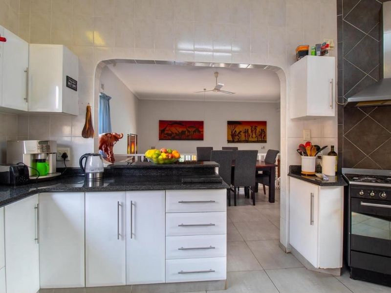 Functional kitchen featuring white cabinetry, granite countertops, and a gas stove, with an open-plan layout connecting to the dining area.