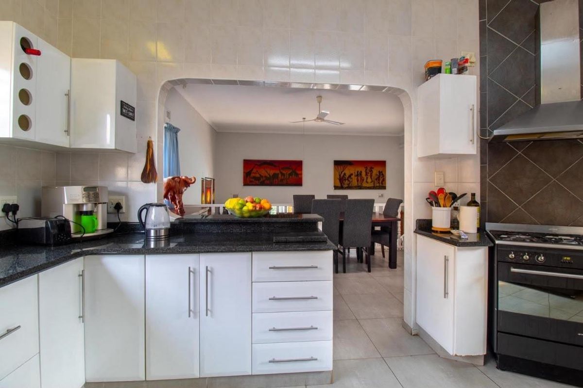 Functional kitchen featuring white cabinetry, granite countertops, and a gas stove, with an open-plan layout connecting to the dining area.