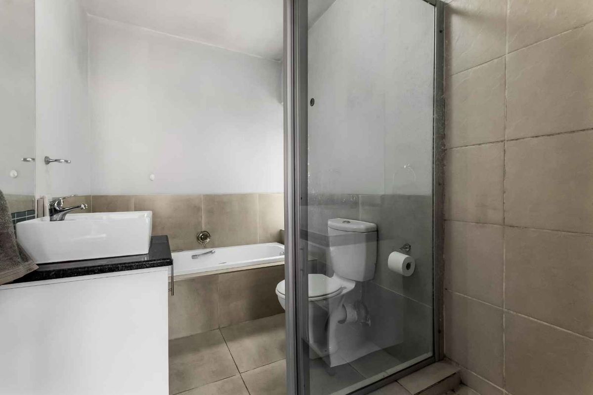 A functional bathroom featuring a glass-enclosed shower, a separate bathtub, a modern vessel sink vanity, and a standard toilet.