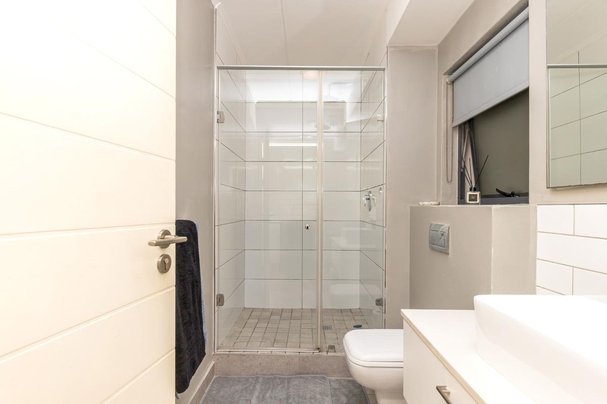 Modern bathroom featuring a glass-enclosed shower, wall-mounted toilet, and a sleek vanity with a vessel sink.