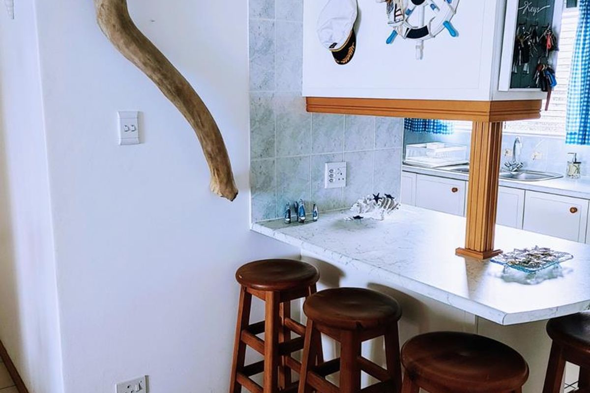 A kitchen breakfast bar area featuring tiled flooring, a laminate countertop, and a wooden support pillar, connecting to the main kitchen space.