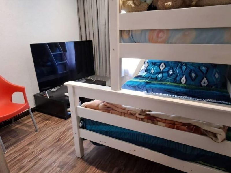 A compact bedroom featuring durable laminate flooring and neutral wall finishes, suitable for a child's room or guest space.