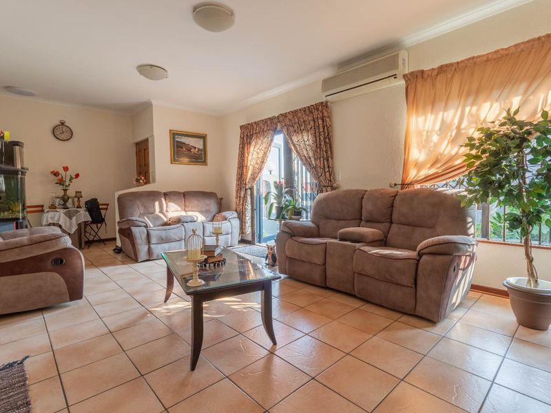 A spacious living room featuring tiled flooring, a wall-mounted air conditioning unit, and a sliding glass door providing access to the exterior.