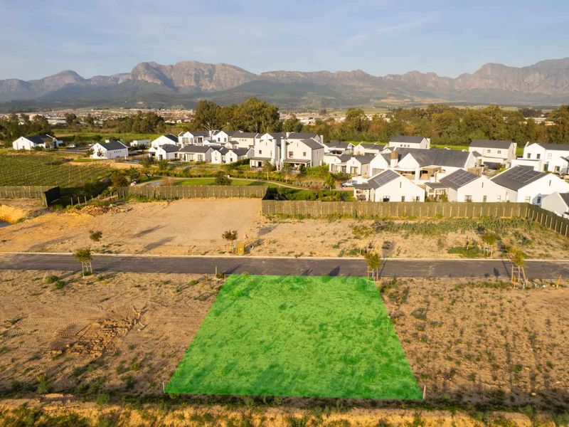 An aerial view of a vacant residential plot in a developed estate, featuring mountain views and established surrounding infrastructure.