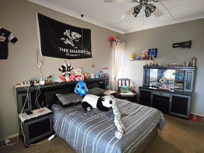 A bedroom featuring a ceiling fan, built-in headboard, and integrated vanity unit, with carpeted flooring throughout.