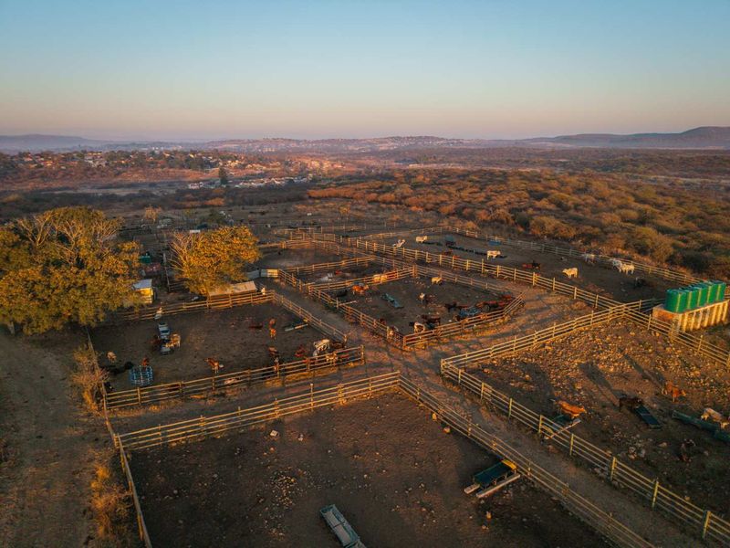 Aerial view of a rural property featuring extensive livestock enclosures, fencing, and water storage infrastructure set within a natural landscape.