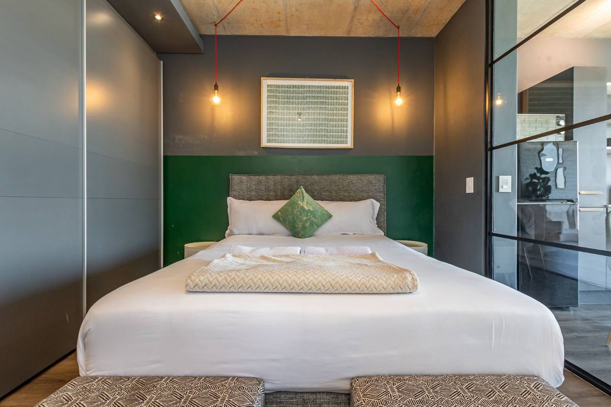 Modern bedroom featuring a concrete ceiling, built-in grey cabinetry, and a glass partition wall, creating a contemporary and stylish living space.