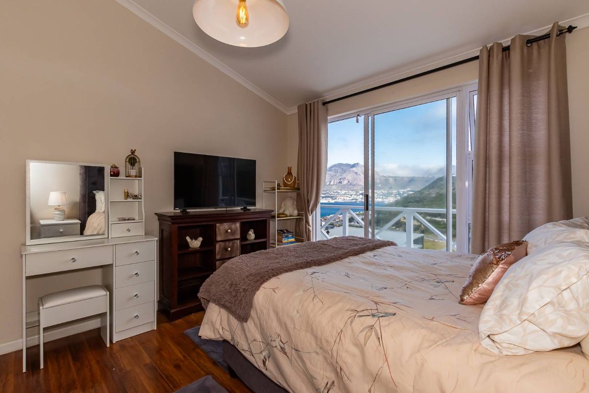 A well-maintained bedroom featuring hardwood flooring and a large sliding glass door that opens to a scenic mountain and coastal view.
