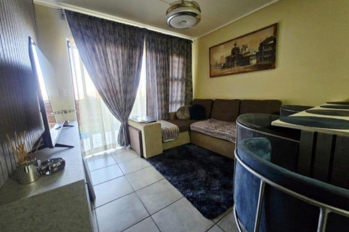 A compact living room featuring tiled flooring, a ceiling fan, and a sliding glass door providing access to an outdoor area.