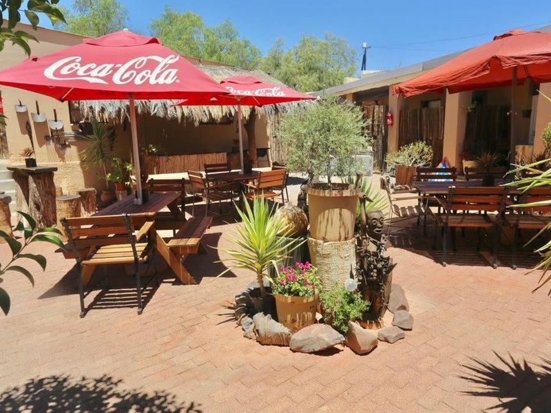 An outdoor patio area featuring paved flooring and a thatched roof structure, suitable for guest seating and relaxation.