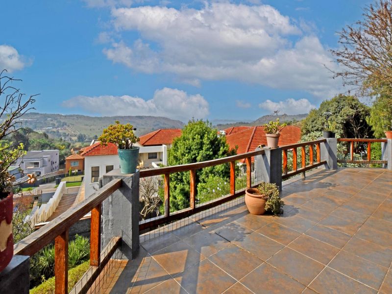 Spacious elevated balcony featuring tiled flooring, a wooden balustrade with wire mesh, and expansive views of the surrounding neighborhood and hills.