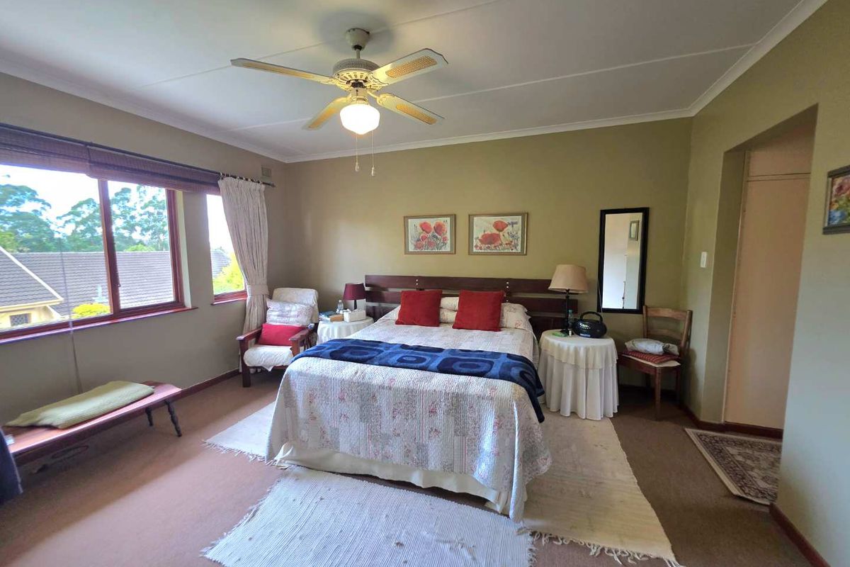 A spacious bedroom featuring carpeted flooring, a ceiling fan, and built-in storage, offering a comfortable and functional living space.