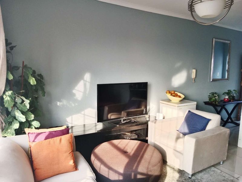 A comfortable living room area featuring neutral tiled flooring and a feature wall, providing a functional space for relaxation.