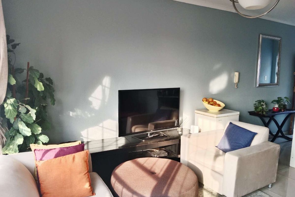 A comfortable living room area featuring neutral tiled flooring and a feature wall, providing a functional space for relaxation.