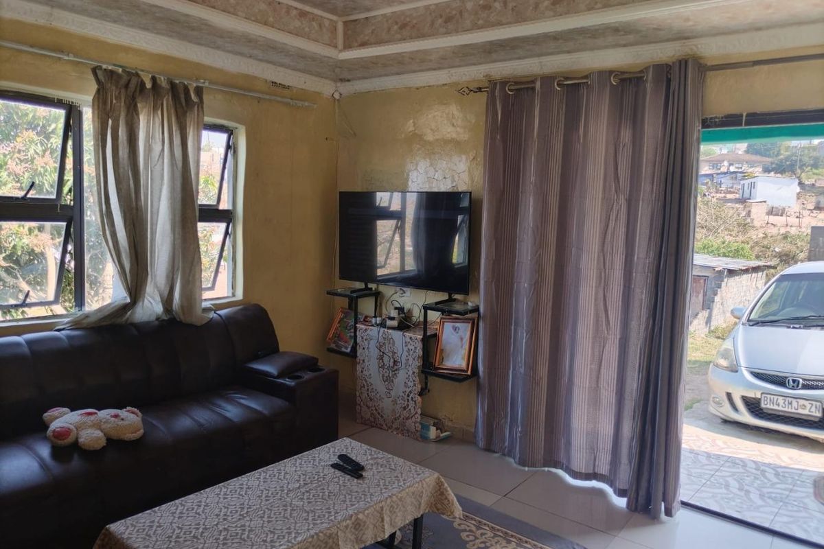A living room featuring tiled flooring, a tray ceiling, and direct access to the exterior through a sliding door.