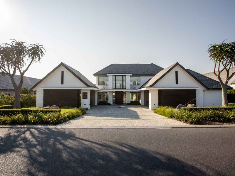 A modern, well-maintained front elevation featuring a double garage, paved driveway, and manicured landscaping, showcasing excellent curb appeal.