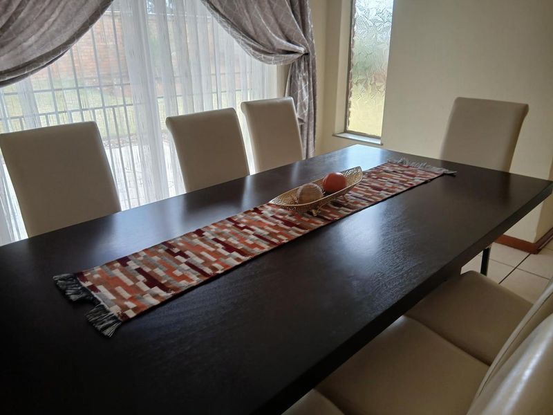 A dining room featuring tiled flooring, a sliding glass door providing natural light, and a frosted glass window.