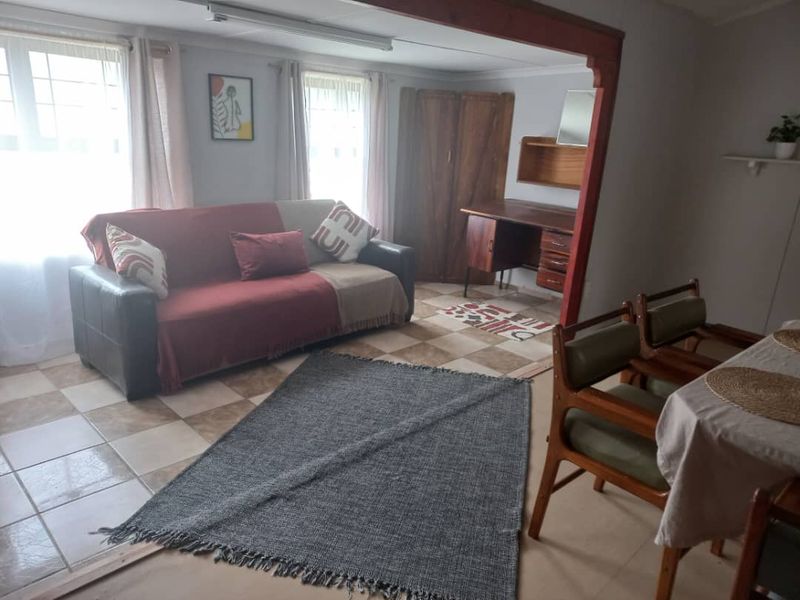 Open plan living and dining area featuring tiled flooring and a prominent exposed timber beam, offering a versatile space for relaxation and meals.