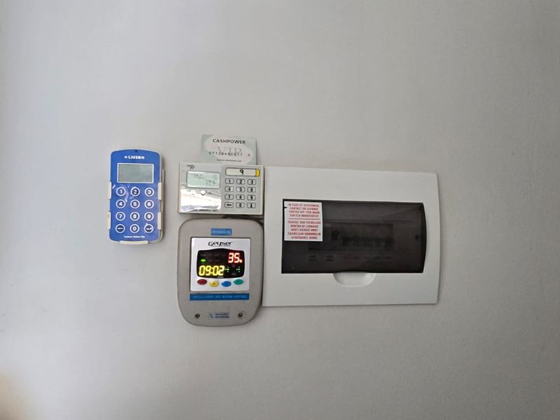 Wall-mounted utility panel featuring a prepaid electricity meter, geyser timer controller, and the main electrical distribution board.