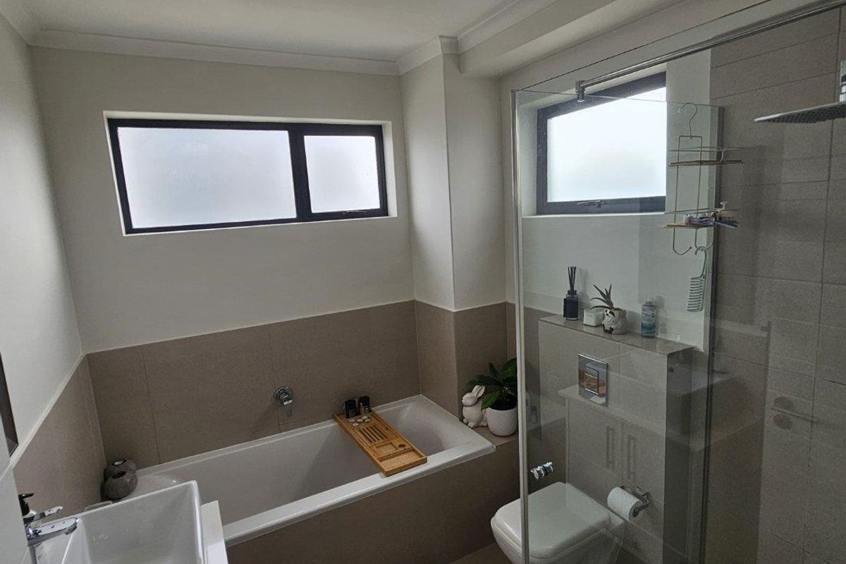 Modern bathroom featuring a built-in bathtub, wall-mounted toilet, glass-enclosed shower, and a contemporary vessel sink with neutral tiling.