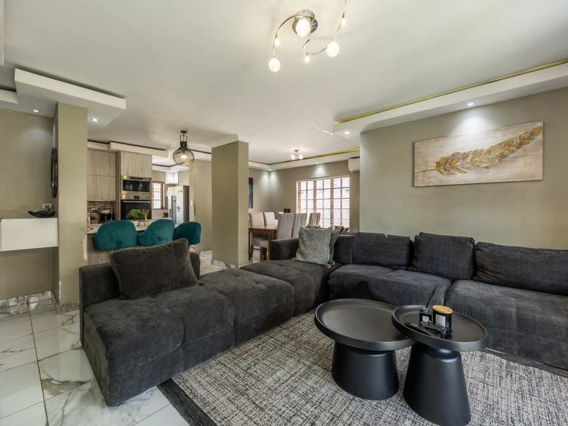 Spacious open-plan living area featuring marble-look flooring, modern recessed lighting, and a well-integrated kitchen with built-in appliances and a breakfast bar.