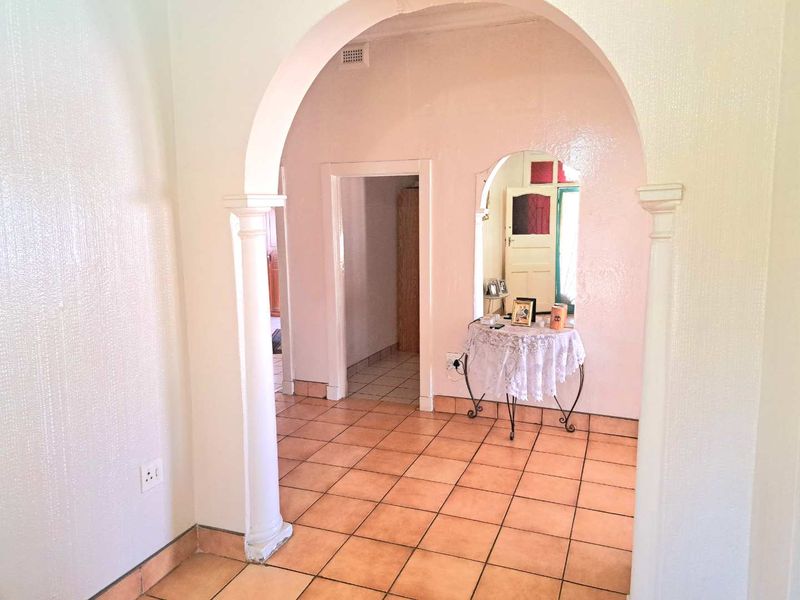 A bright hallway featuring classic arched doorways, ceramic tiled flooring, and a built-in wall niche, providing a functional transition space between rooms.