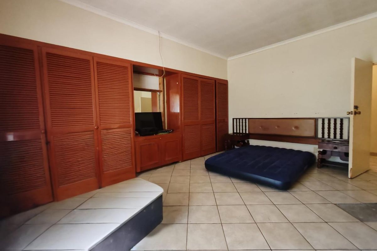Spacious bedroom featuring extensive built-in wooden cabinetry and tiled flooring, offering ample storage space and a neutral layout.