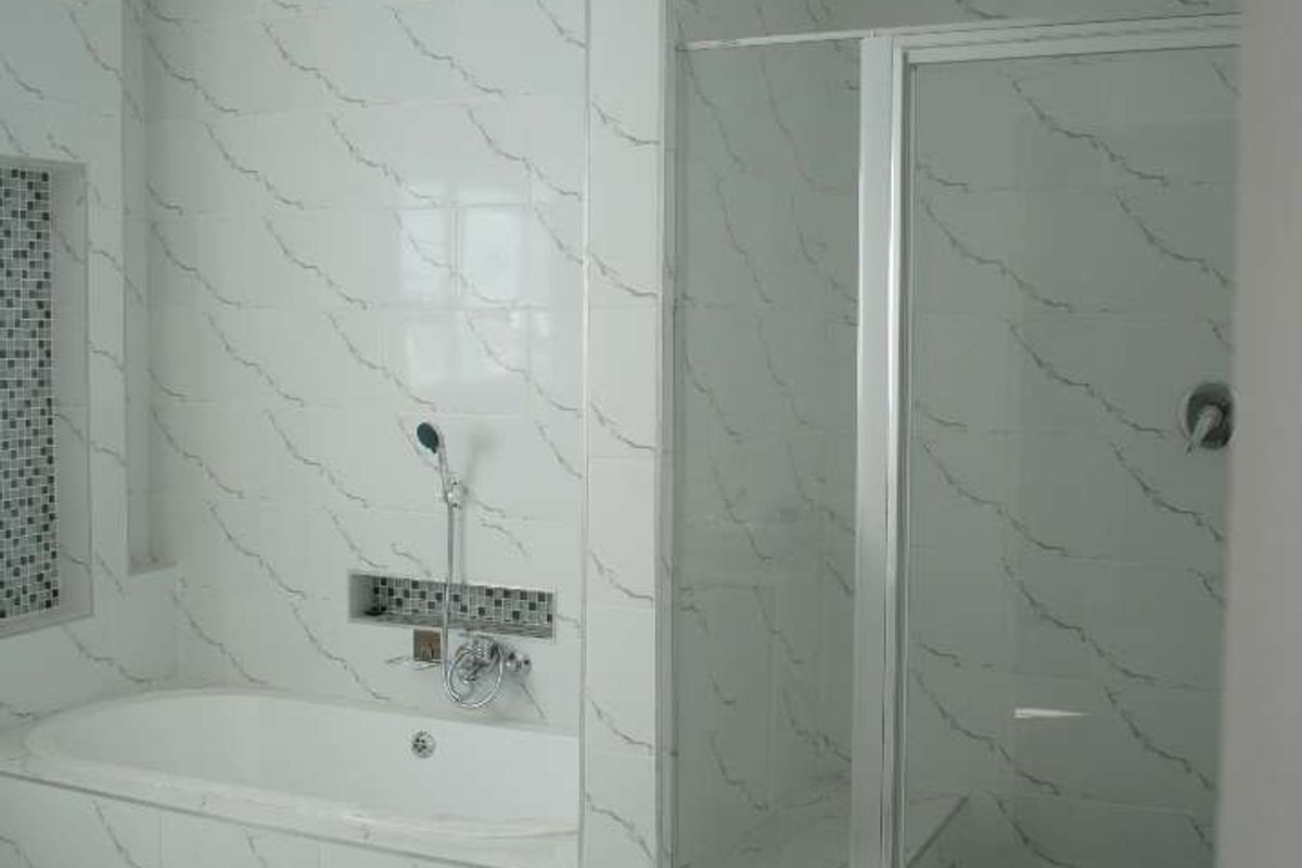 Modern bathroom featuring a built-in bathtub with handheld shower fixture and a separate glass-enclosed shower stall with tiled finishes.