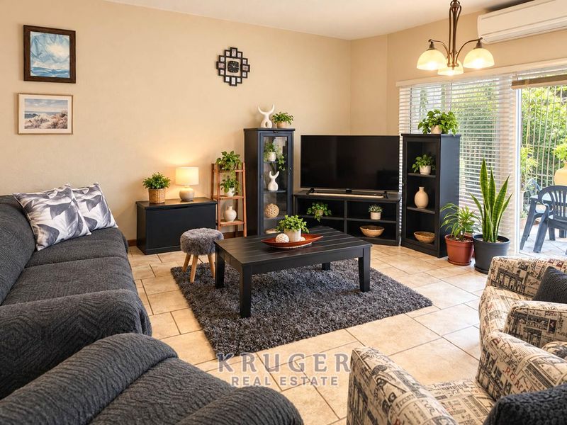A comfortable living room featuring tiled flooring, a split-system air conditioner, and a sliding glass door providing access to the outdoor area.