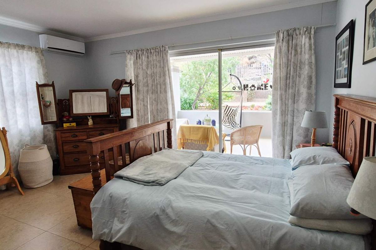 Spacious bedroom featuring tiled flooring, crown molding, a wall-mounted air conditioning unit, and sliding glass doors providing direct access to an outdoor patio area.