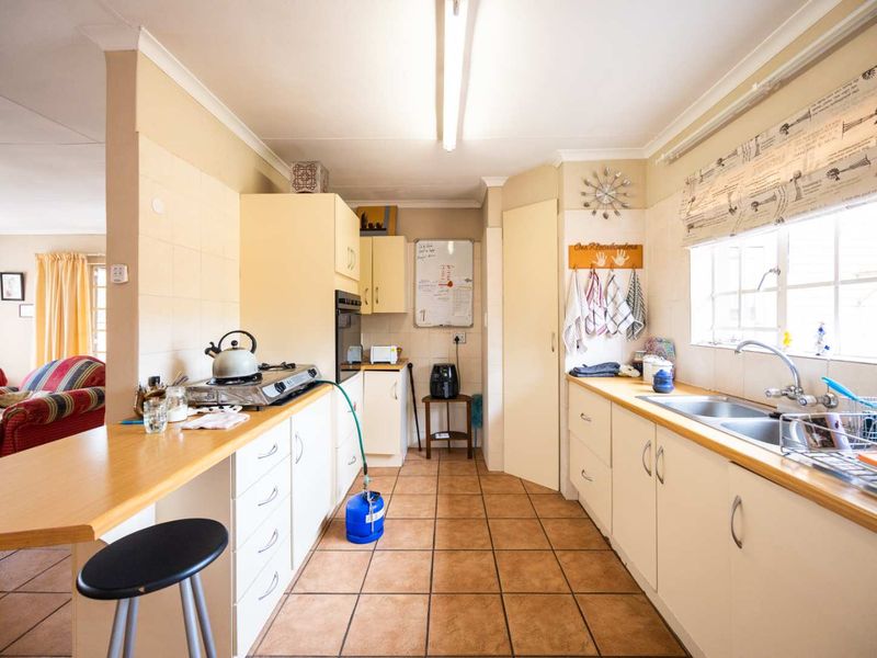 A functional kitchen featuring built-in cabinetry, laminate countertops, a double basin sink, and tiled flooring, offering a practical layout for daily meal preparation.