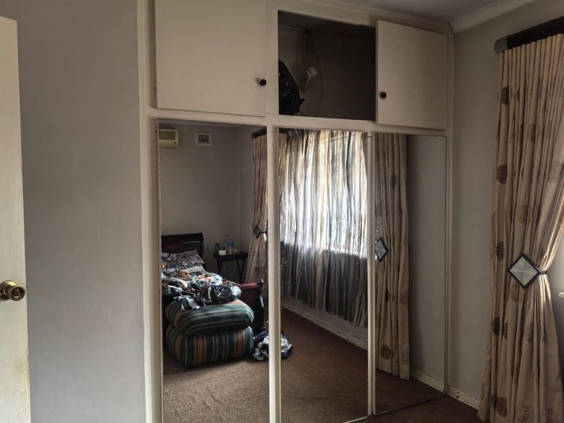 Bedroom featuring built-in mirrored wardrobes with overhead storage and a wall-mounted air conditioning unit.