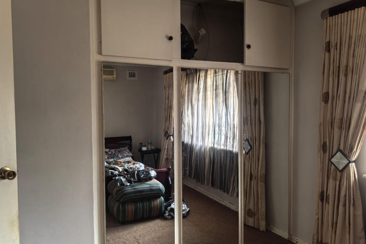 Bedroom featuring built-in mirrored wardrobes with overhead storage and a wall-mounted air conditioning unit.