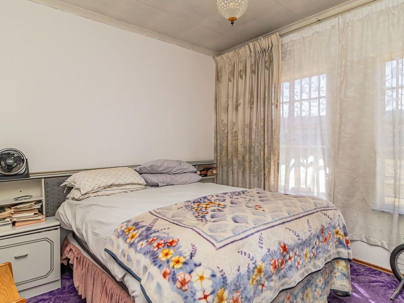 A bedroom featuring a built-in headboard, window with security bars, and carpet flooring, offering a functional space ready for cosmetic updates.