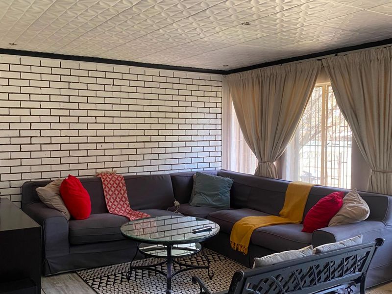 A living room featuring a white painted exposed brick feature wall and a textured ceiling, providing a distinct character to the space.