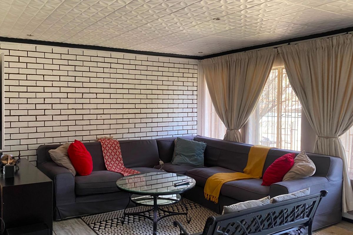 A living room featuring a white painted exposed brick feature wall and a textured ceiling, providing a distinct character to the space.
