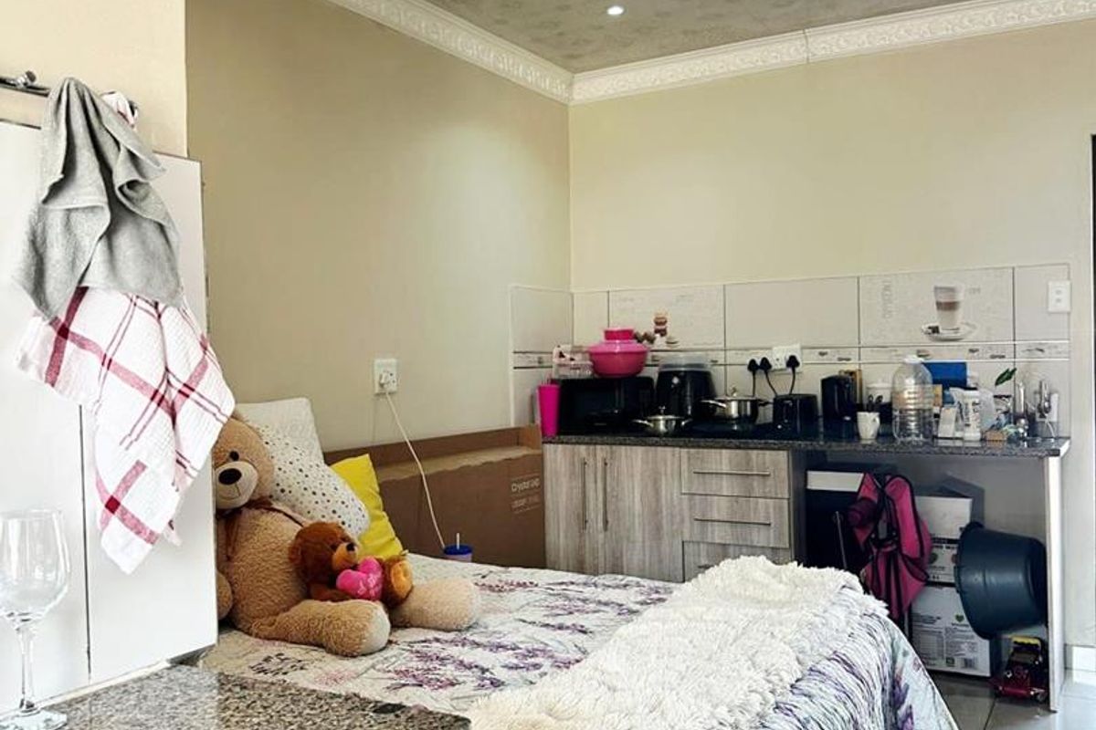Compact open-plan studio apartment featuring a kitchenette with granite countertops, tiled flooring, and decorative ceiling finishes.