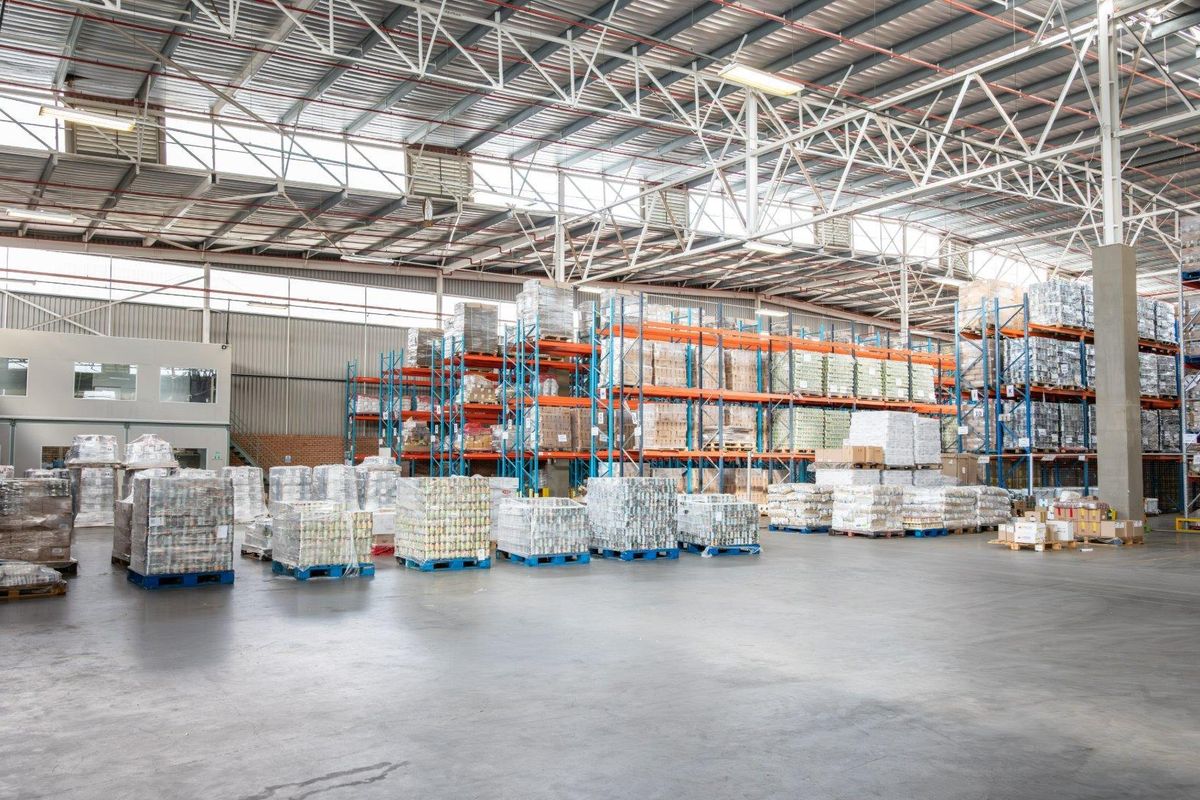 Spacious industrial warehouse featuring high-clearance steel truss roofing, polished concrete flooring, and extensive integrated racking systems for efficient storage and logistics operations.