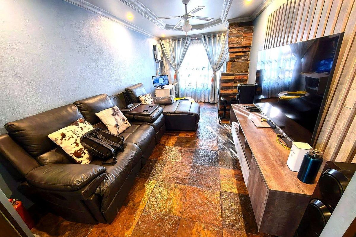 A living room featuring textured stone flooring, decorative wall paneling, and a ceiling fan with integrated cove lighting.