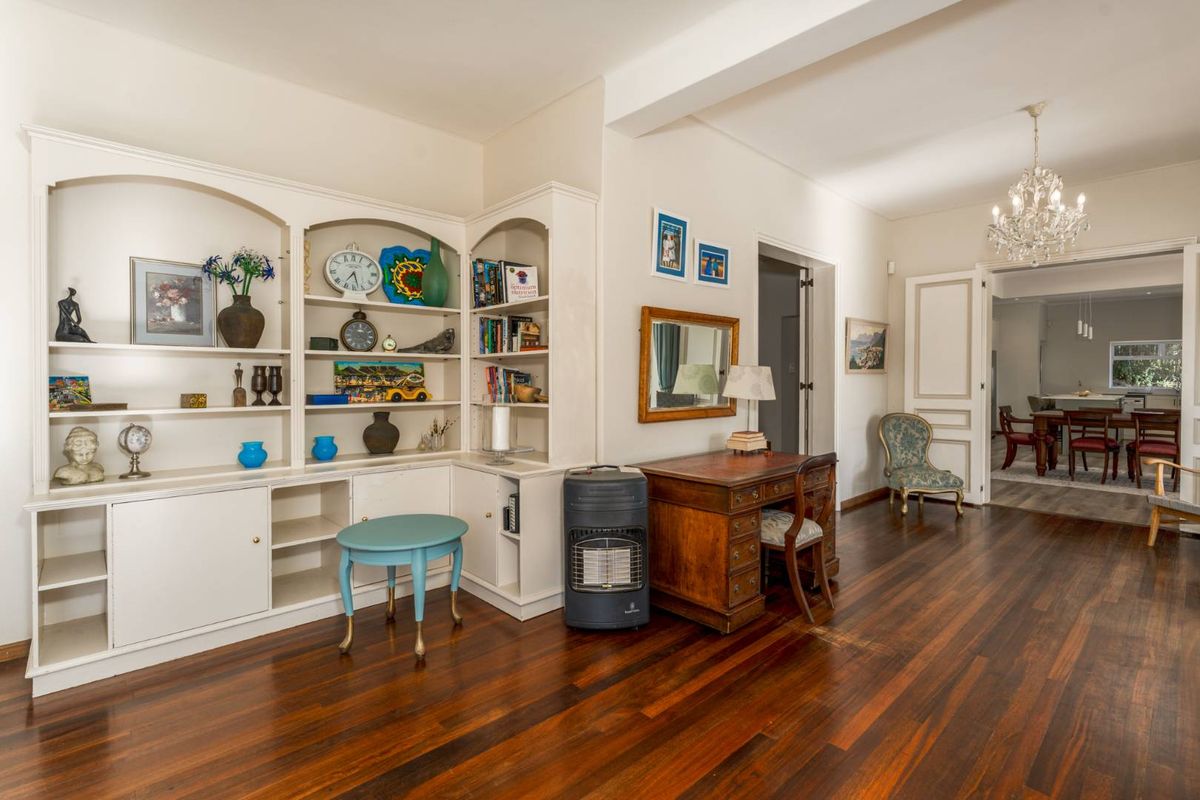 Spacious living area featuring polished hardwood flooring, a custom built-in shelving unit, and elegant double doors leading to the dining room.